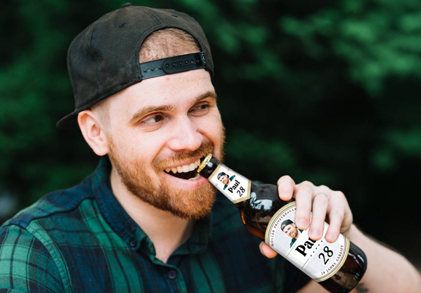 Mann hält personalisierte Bierflasche mit individuellen Stickern als Geschenk in der Hand